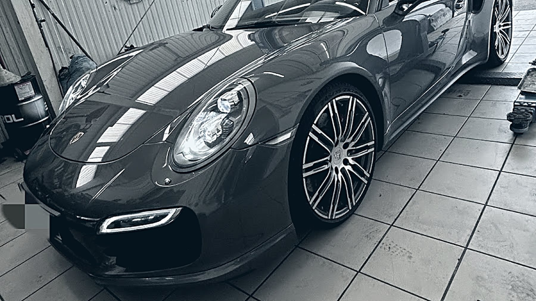 Porsche 911 Turbo Cabrio auf dem gefliesten Hallenboden der Werkstatt Car Care Krems, Kennzeichen unkenntlich gemacht