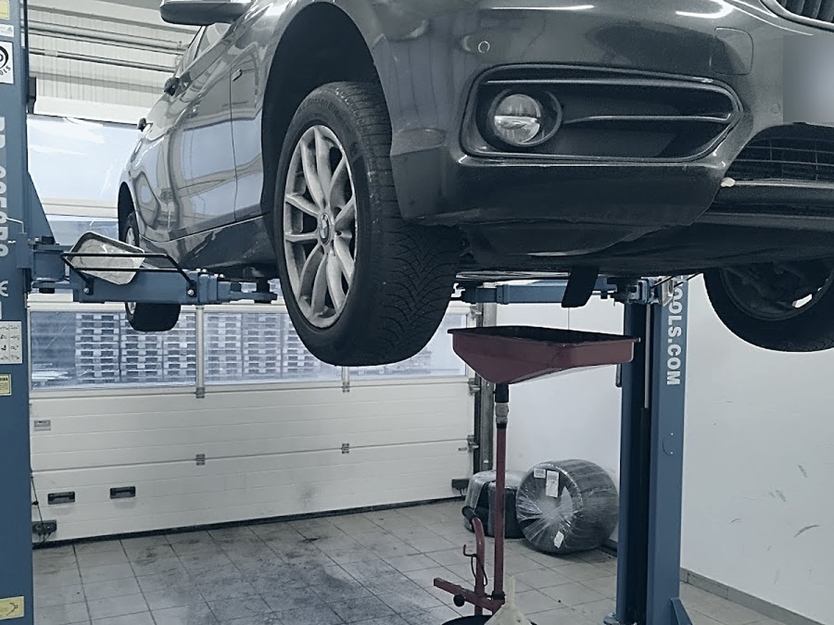 Service bei Car Care Krems: BMW auf der Hebebühne, Ölauffangwanne darunter